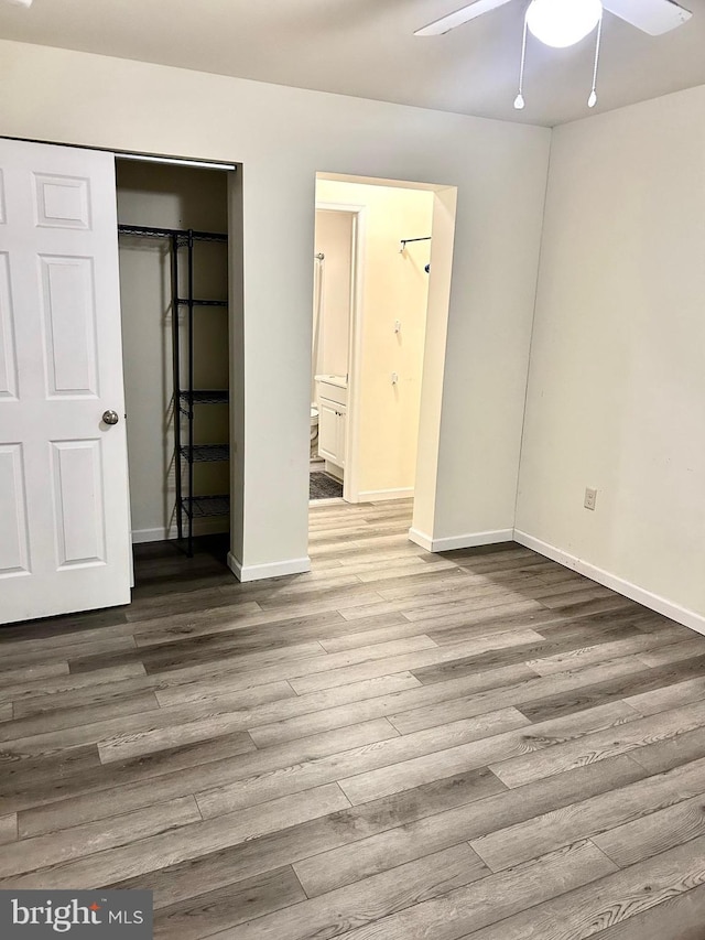 unfurnished bedroom with connected bathroom, hardwood / wood-style floors, and ceiling fan