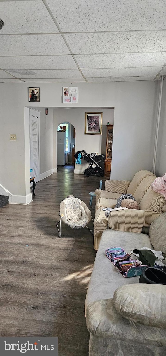 living room featuring wood-type flooring and a drop ceiling