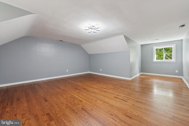 additional living space featuring lofted ceiling and light hardwood / wood-style flooring