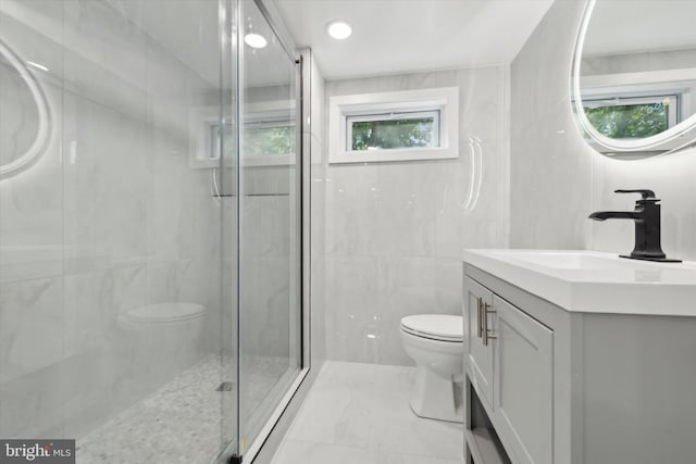 bathroom featuring vanity, toilet, tile walls, and a shower with shower door