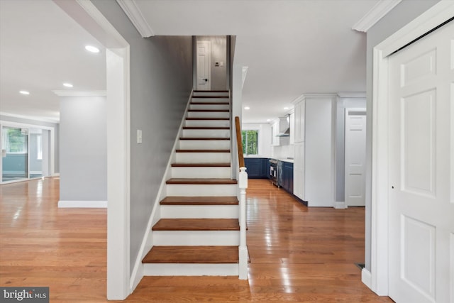 stairway with hardwood / wood-style flooring and crown molding