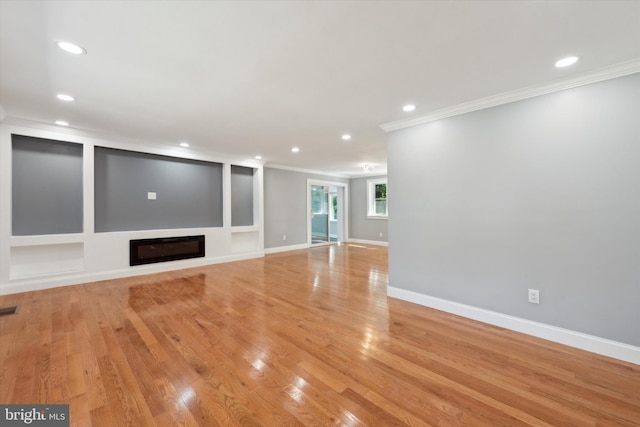 unfurnished living room with built in shelves, crown molding, and light wood-type flooring