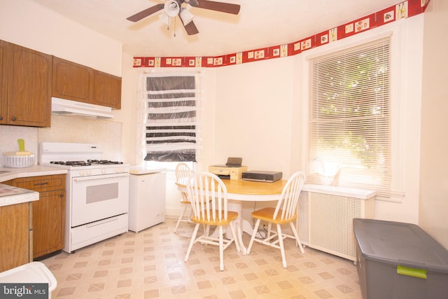 kitchen featuring ceiling fan, white range with gas cooktop, and decorative backsplash