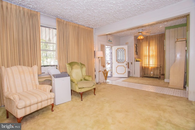 living area with a textured ceiling, ceiling fan, and carpet flooring