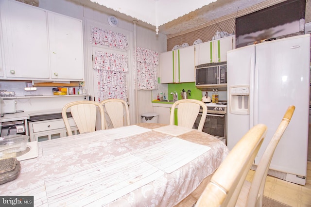 interior space with white cabinets, white fridge with ice dispenser, stainless steel stove, and sink