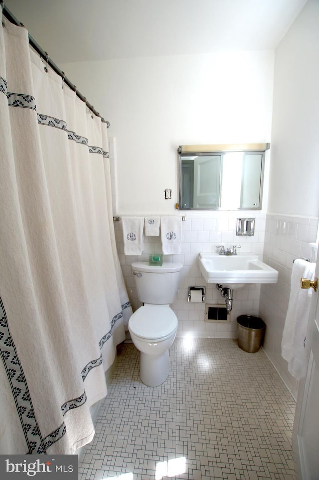 bathroom with tile walls, tile patterned flooring, sink, a shower with curtain, and toilet