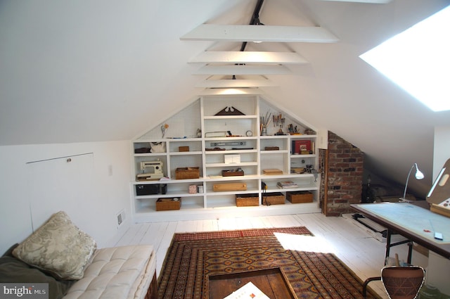 additional living space featuring vaulted ceiling with beams and light hardwood / wood-style flooring