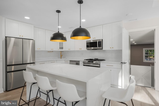 kitchen with light wood-style flooring, white cabinetry, backsplash, and stainless steel appliances