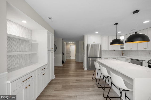 kitchen featuring a center island, open shelves, white cabinets, stainless steel appliances, and a sink