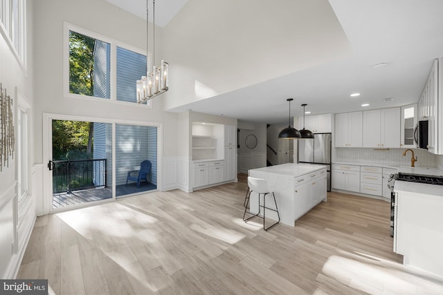 kitchen featuring a wealth of natural light, a towering ceiling, a center island, appliances with stainless steel finishes, and a breakfast bar area