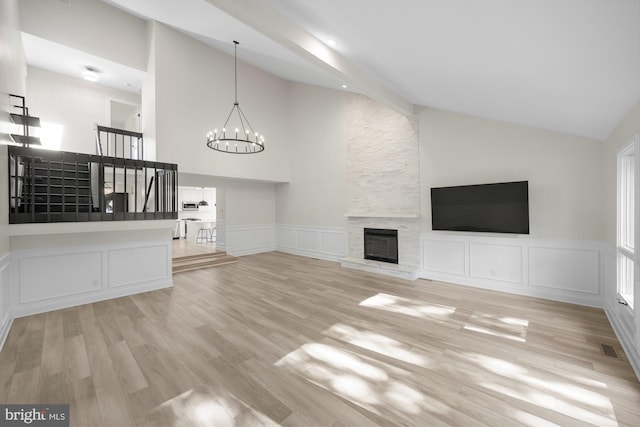 unfurnished living room with a chandelier, a decorative wall, wood finished floors, and a fireplace