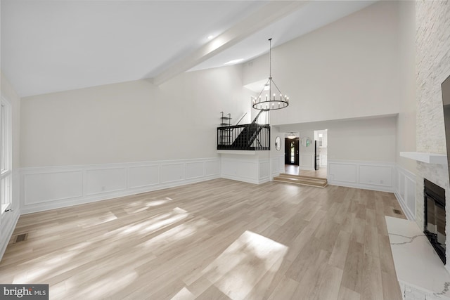 unfurnished living room with lofted ceiling with beams, visible vents, a fireplace, and light wood finished floors