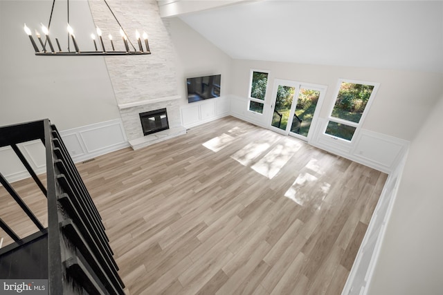 unfurnished living room with a decorative wall, an inviting chandelier, a wainscoted wall, and lofted ceiling with beams