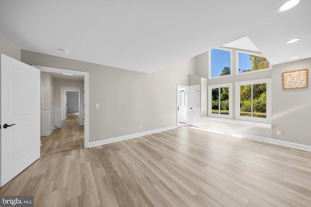 unfurnished living room with a high ceiling, light wood finished floors, baseboards, and recessed lighting