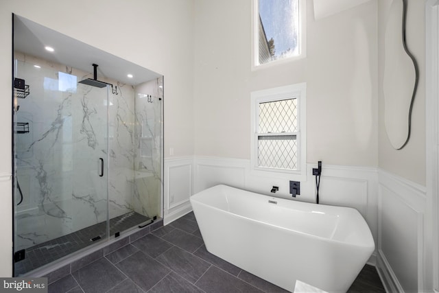 full bathroom with a marble finish shower, a decorative wall, wainscoting, recessed lighting, and a soaking tub