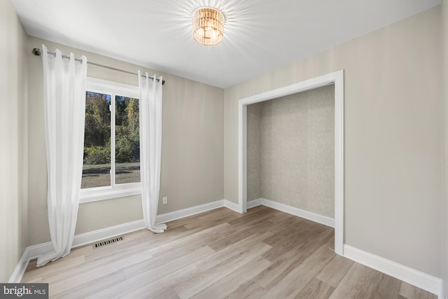 unfurnished bedroom with visible vents, baseboards, wood finished floors, and a chandelier