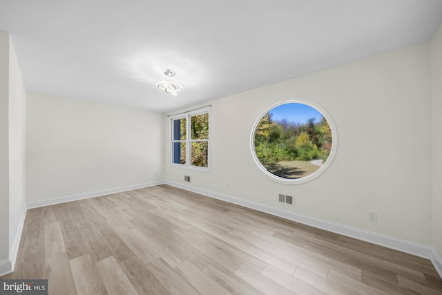 empty room with visible vents, light wood-type flooring, and baseboards