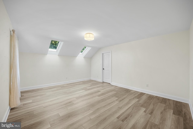 bonus room featuring baseboards, lofted ceiling with skylight, and light wood-style flooring