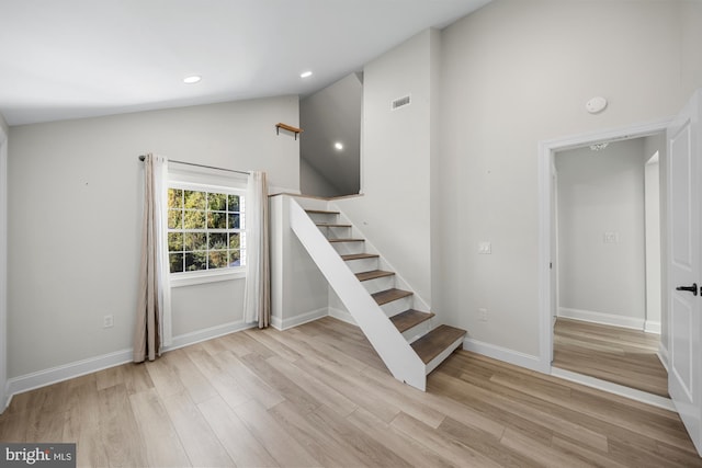 staircase featuring wood finished floors, visible vents, baseboards, lofted ceiling, and recessed lighting