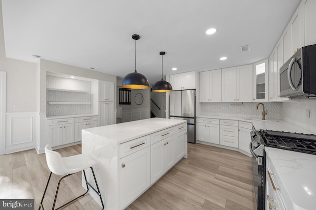 kitchen featuring visible vents, light stone countertops, a kitchen island, and appliances with stainless steel finishes