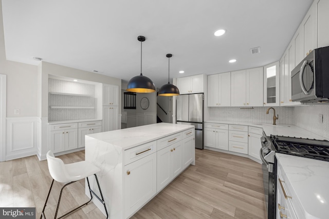 kitchen featuring visible vents, a center island, appliances with stainless steel finishes, and light stone counters
