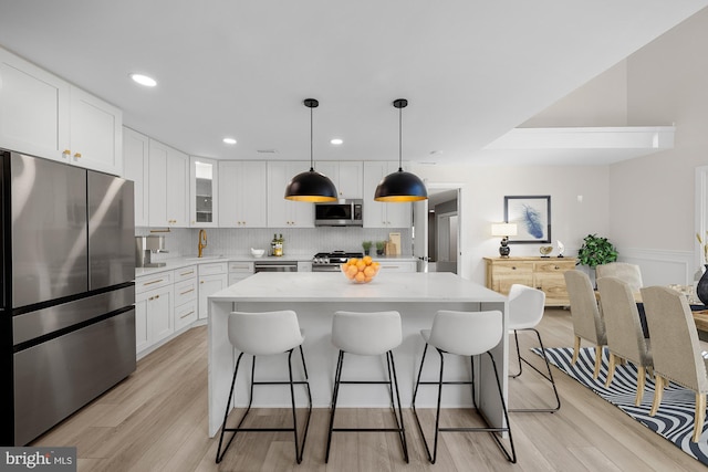 kitchen featuring decorative backsplash, a kitchen breakfast bar, white cabinets, and appliances with stainless steel finishes