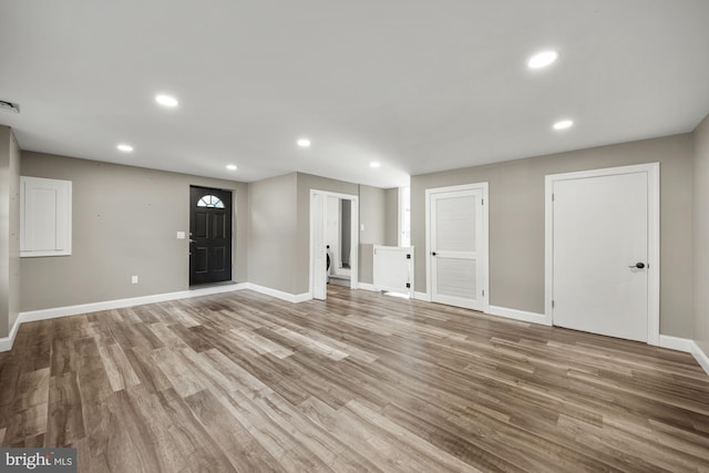 unfurnished living room with recessed lighting, baseboards, and wood finished floors