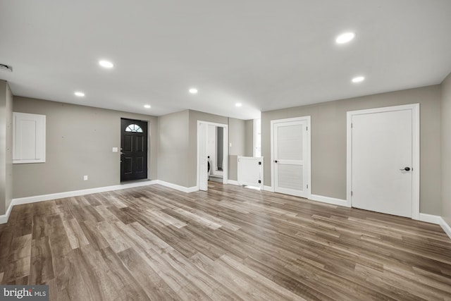 unfurnished living room with wood finished floors, baseboards, and recessed lighting