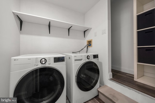 washroom featuring washer and clothes dryer, laundry area, baseboards, and wood finished floors