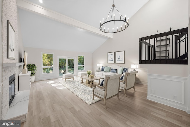 living area featuring a chandelier, a fireplace, beamed ceiling, light wood finished floors, and high vaulted ceiling