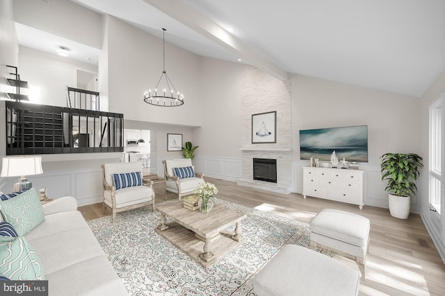 living area with visible vents, an inviting chandelier, a fireplace, wood finished floors, and high vaulted ceiling
