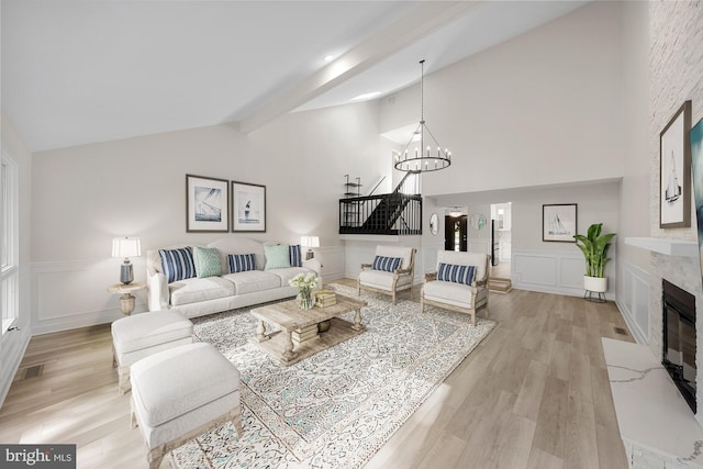 living area with beam ceiling, a fireplace with flush hearth, visible vents, and light wood-type flooring