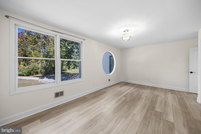 unfurnished room featuring visible vents, light wood-type flooring, and baseboards