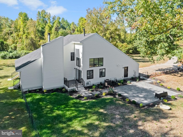 rear view of property featuring central air condition unit, a yard, and a patio area
