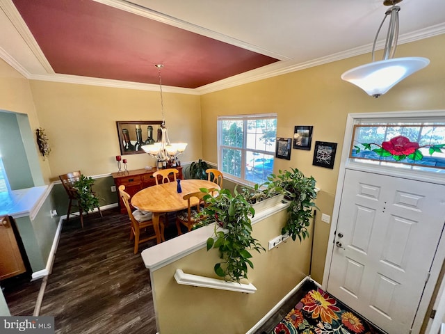 dining space with dark hardwood / wood-style flooring, ornamental molding, and a notable chandelier