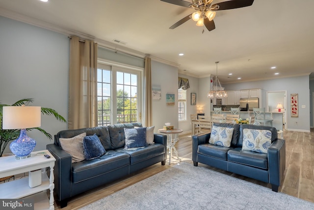 living room with ceiling fan with notable chandelier, crown molding, and light hardwood / wood-style flooring