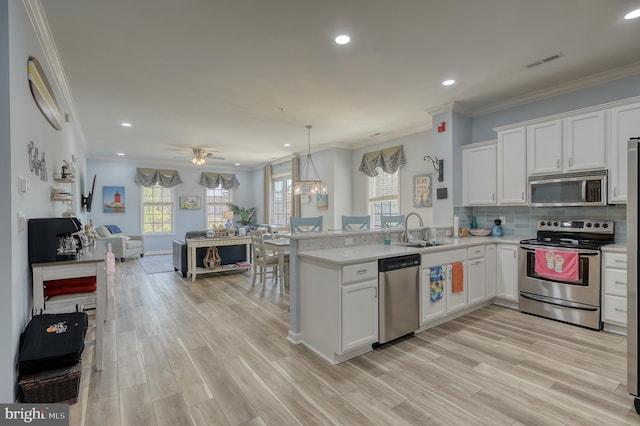 kitchen with light hardwood / wood-style flooring, kitchen peninsula, appliances with stainless steel finishes, and white cabinetry