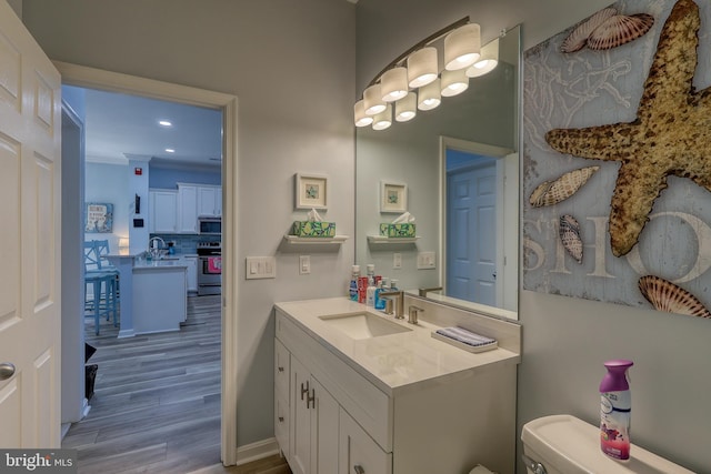 bathroom with toilet, ornamental molding, vanity, tasteful backsplash, and wood-type flooring