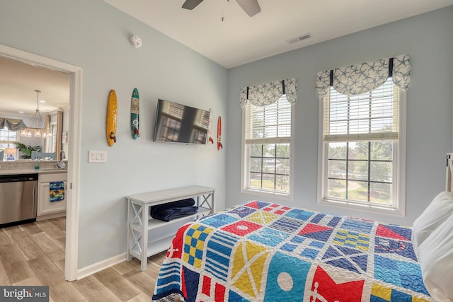 bedroom with light wood-type flooring, ceiling fan with notable chandelier, and sink