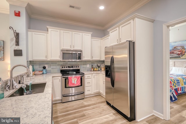 kitchen featuring light stone countertops, stainless steel appliances, light hardwood / wood-style floors, and sink