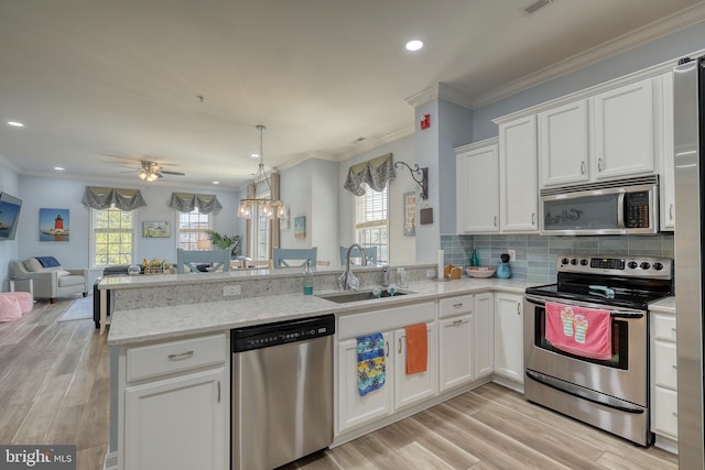 kitchen with white cabinets, appliances with stainless steel finishes, and light hardwood / wood-style flooring