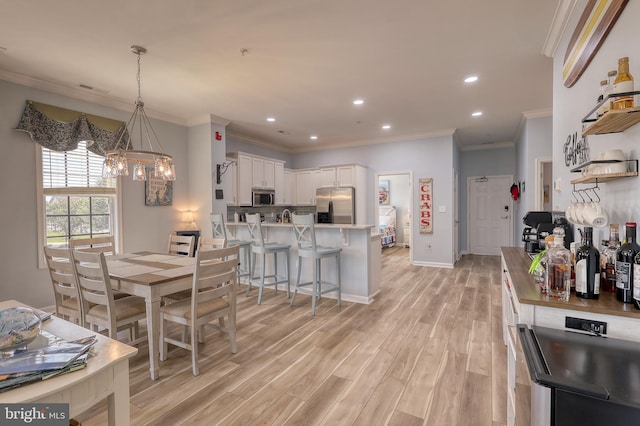 dining space featuring ornamental molding and light hardwood / wood-style floors