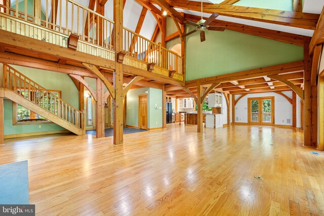 unfurnished living room with beamed ceiling, high vaulted ceiling, ceiling fan, and light hardwood / wood-style floors