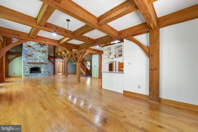 unfurnished living room featuring a fireplace, beamed ceiling, light hardwood / wood-style flooring, and coffered ceiling