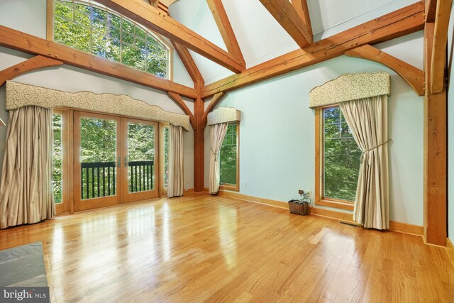 interior space with high vaulted ceiling, wood-type flooring, plenty of natural light, and french doors