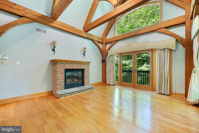 unfurnished living room with high vaulted ceiling, a fireplace, and light hardwood / wood-style floors