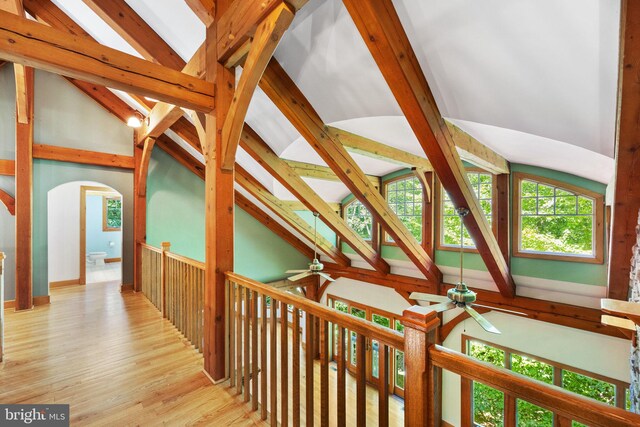 corridor with light wood-type flooring, high vaulted ceiling, and beam ceiling