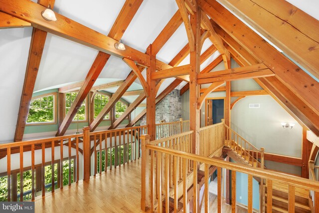 hall with light wood-type flooring and vaulted ceiling with beams