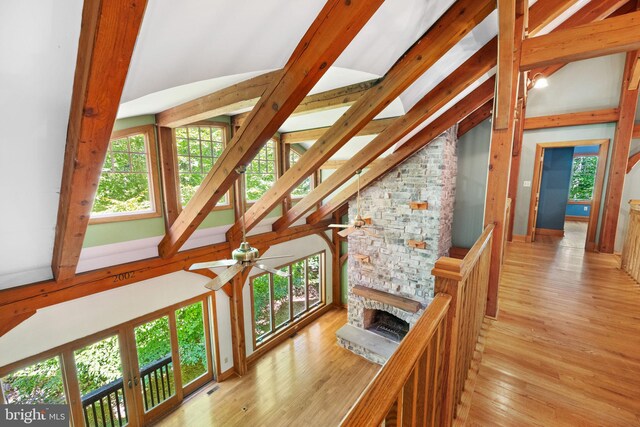 hallway featuring light wood-type flooring, high vaulted ceiling, a healthy amount of sunlight, and beam ceiling