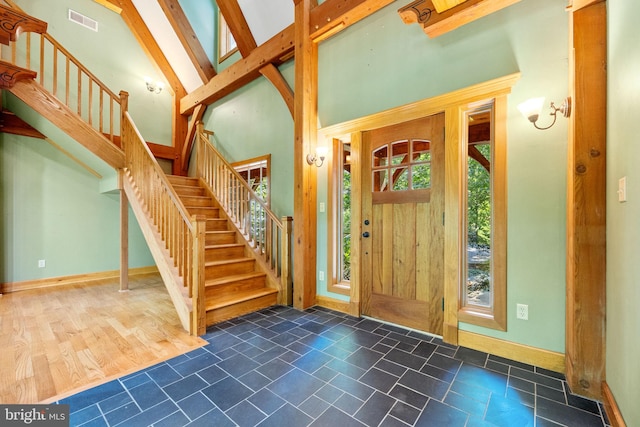 entrance foyer with beamed ceiling, high vaulted ceiling, and dark tile patterned flooring